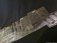 Wide view of all eleven clear plastic mold sheets laid out showing various cavity designs.