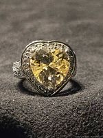 Frontal view of ring showing heart-cut yellow stone and halo of clear stones