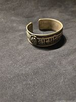 Front view of metal cuff showing Tibetan script