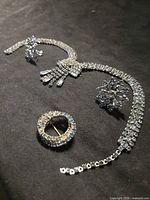 Necklace, earrings, brooch on black surface close view