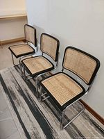 Front angled view of three identical cane cantilever chairs