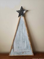 Front view of wooden Christmas tree wall art showing metal star and distressed finish