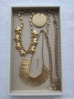 Tray showing all three necklaces, large disc charm, small bar charm