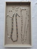 Full lot showing three necklaces, three earring pairs and tray