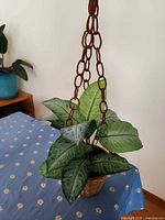 Full view of hanging wicker basket with faux plant on table