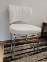 Front-angle view of white faux leather chair showing seat, backrest and chrome base