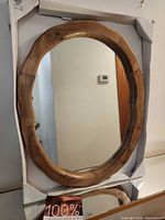 Front view of oval wood mirror in packaging