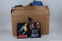 Front view of taped cardboard box labeled DVD with two representative DVD cases displayed