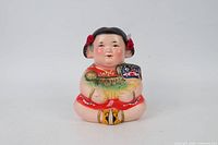 Front view of porcelain child piggy bank showing painted details and colours