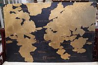 Front view of gold-on-black world map canvas
