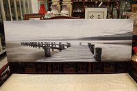Front view of the panoramic lake pier canvas print displayed on a bench