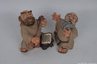 Both monk figurines side by side showing overall design and scale