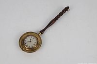 Full view of brass warming-pan style clock with turned wooden handle