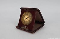 Clock displayed open showing dial and leather case