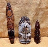 Front view of all three wooden masks standing side by side