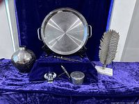 Overview showing griddle, speckled vase, chopsticks, lidded box, corkscrew and metal leaf sculpture