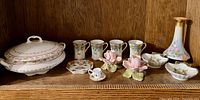 Full lot on shelf showing tureen, candle holders, cups, vase, small dishes