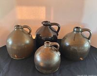 All four brown-glazed stoneware jugs grouped