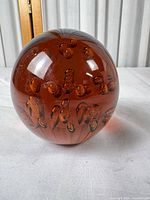 Full view of amber glass paperweight showing color and bubbles