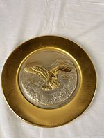 Front view showing gold-tone rim and raised eagle design