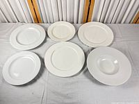 Overview of six assorted white plates laid out