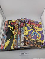 Stack of assorted comics topped with Surge issue