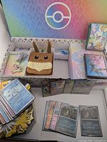 Box interior with Eevee deck box, tin, card stacks, sealed sleeve packs