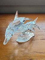 front view of clear faceted crystal dolphin figurine showing two dolphins on wave base