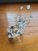 Full view of clear crystal clown figurine showing wire hoop with six crystal beads and green bow tie