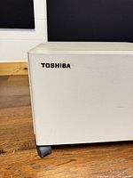 Front left corner showing Toshiba logo, paint finish, casters visible