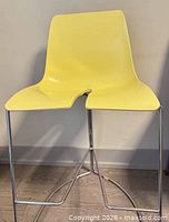 Front view of yellow molded plastic counter stool on chrome frame