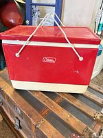 Front angled view of red and white Coleman cooler with handles down