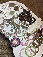 Mixed jewelry laid out showing necklaces, earrings and bracelets