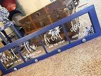Full view of blue four-pane window coat rack with lettering and knobs