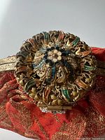 Close-up of ornate enamel beaded clasp on orange and gold brocade purse