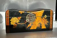 Front view showing lacquer finish, gilt motifs, and metal clasp with key