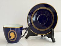 Cup and saucer front view showing cobalt glaze, gold portrait and banding