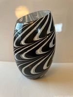 Front three-quarter view of black and white swirl art glass vase