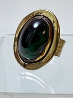 Front view showing oval green glass cabochon set in hammered brass bezel