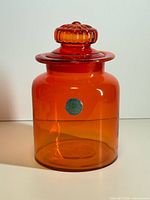 Full view of orange glass jar with lid and label visible