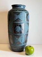 Front view of tall teal and dark blue geometric West German vase with apple for scale