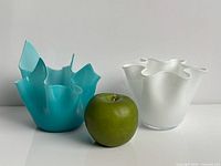 Teal and white vases side by side with apple for scale