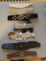 Group shot of eight vintage evening belts laid out on table