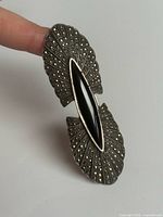 Brooch on finger showing front details, marcasite pattern and black onyx