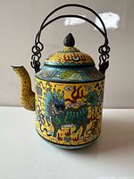 Front view showing dragon design, spout, handles and lid
