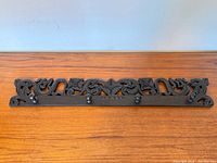 Full view of carved wood coat rack showing four pegs and overall design