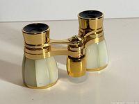 Front three-quarter view of opera glasses showing gold-tone finish and mother-of-pearl barrels