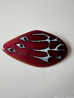Front view of enamel brooch showing abstract bird design