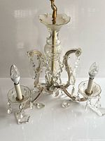 Front view of Murano glass chandelier showing three arms, crystal drops, candle sockets