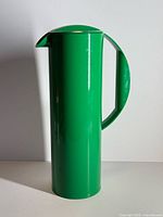 Full left side view showing tall slim green pitcher with handle